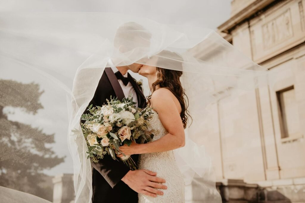 Tu Creador de Contenido Bride and groom share a tender kiss under a veil, showcasing love and romance on their special day.